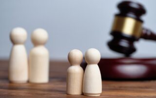 How to get Parental Rights Responsibilities Visitation Maine portrayed by 2 wooden parent dolls and 2 wooden children dolls set next to a gavel on a wooden desk.