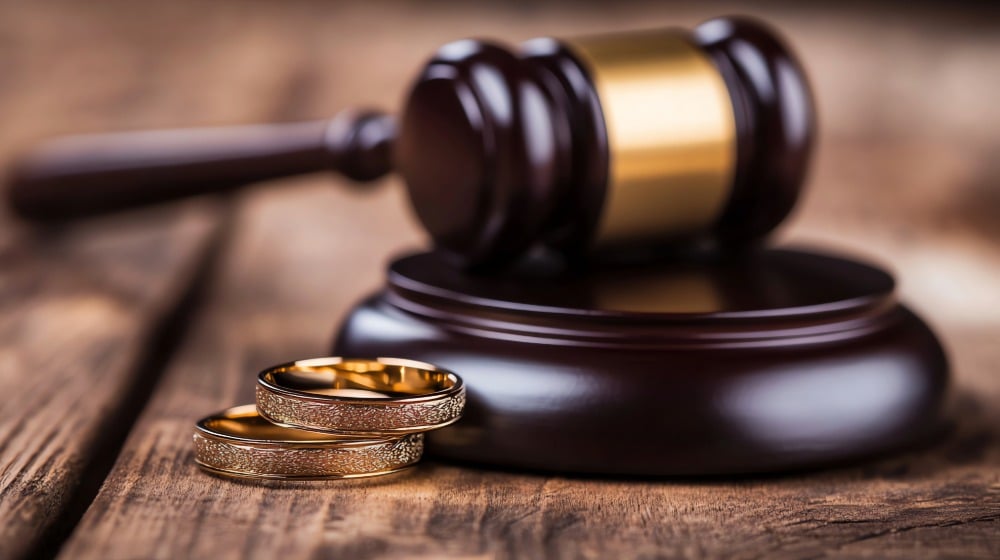 Southern Maine Divorce Lawyers located in Portland, Kennebunk, & Brunswick Maine portrayed by a gavel & two wedding bands on a wooden table.